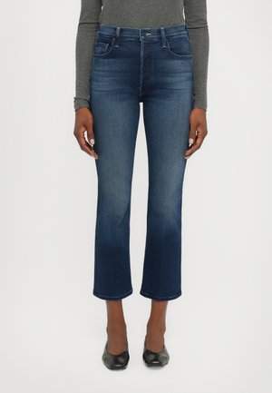 Jeans in denim a vita alta di un blu scuro con fondo svasato. Caratterizzati da cinque tasche e una chiusura con zip. Tessuto liscio.