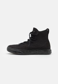 Zwarte hoge gebreide sneakers met een tekstuur oppervlak, zwarte rubberen zolen met kleurrijke spikkels en een traditionele vetersluiting.