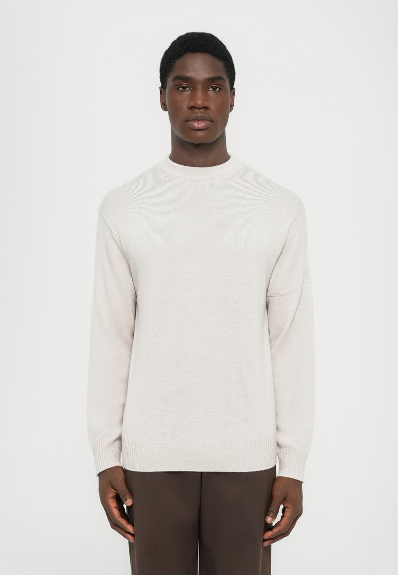 Light gray sweater with a round neckline and long sleeves, featuring ribbed cuffs and hem, made from soft, textured fabric.