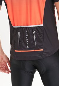 Zwart en oranje fietsjersey met een achterzak, voorzien van reflecterende accenten, korte mouwen en een gladde, rekbare stof.