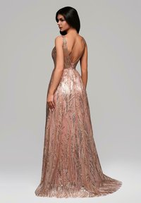 Abito da sera fucsia con paillettes, dal design scoperto sulla schiena, con sottili spalline e una gonna fluente decorata con motivi vegetali.