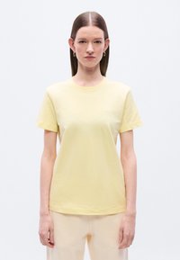 Κίτρινο βαμβακερό μπλουζάκι με στρογγυλή λαιμόκοψη και κοντά μανίκια. Διαθέτει μικρό κεντημένο λογότυπο στο στήθος. Λεία υφή.