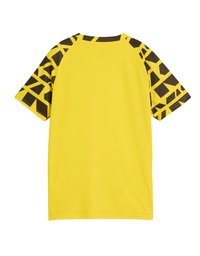 Camiseta deportiva amarilla de manga corta con un patrón geométrico marrón en los hombros. Fabricada con un material texturizado y transpirable.
