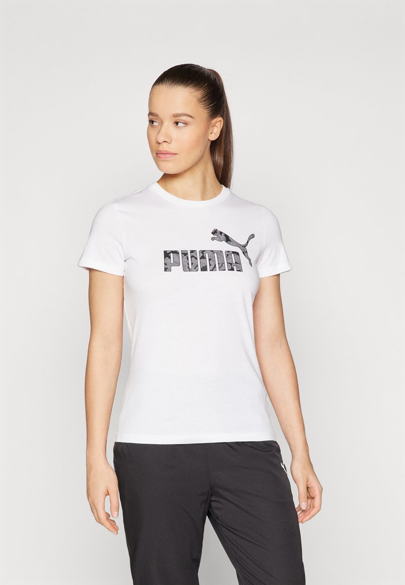Camiseta blanca de manga corta hecha de algodón que presenta un logo de PUMA en camuflaje negro. El corte es estándar, con un cuello redondo y una textura suave.