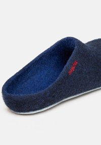 Marine velours pantoffel met een zachte textuur, open ontwerp en rode stikdetails. Bevat een kussentje in de zool en een gebogen bovenrand.