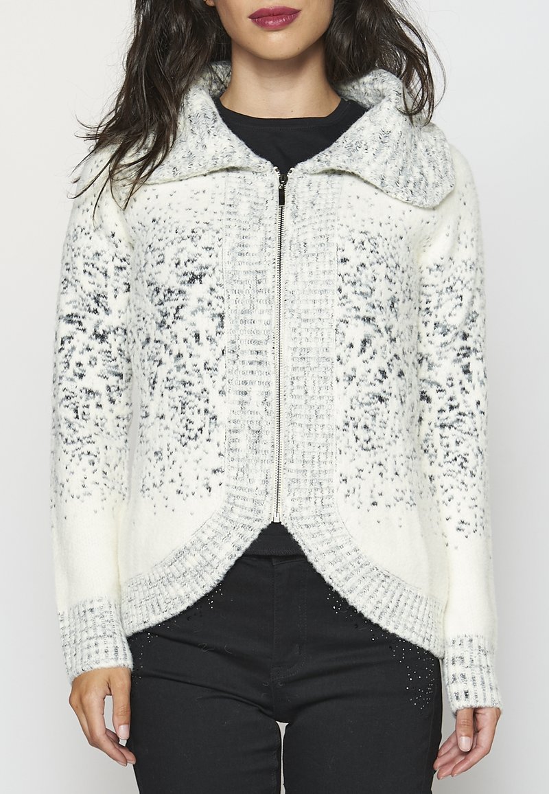 Vit och grå mönstrad zip-up-tröja med bred krage, texturerad stickad design och subtila detaljer vid manschetterna och fållen.