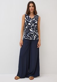 Top senza maniche con scollatura a V, in stampa a foglie blu navy e bianche, abbinato a pantaloni larghi blu navy. Tessuto morbido con una consistenza fluida, vestibilità casual.