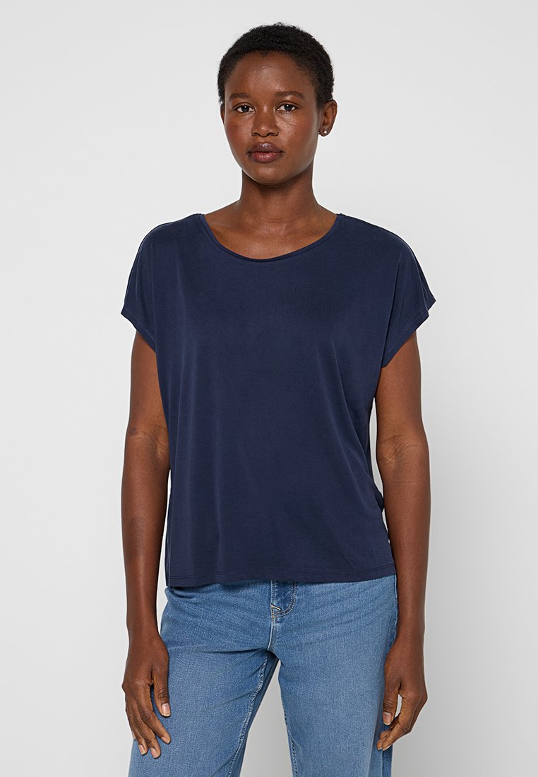 Navyblauwe top met korte mouwen en een ronde hals. Glad materiaal met een relaxte pasvorm, gecombineerd met lichtblauwe jeans.