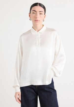 Weißes Poloshirt mit langen Ärmeln aus glattem Stoff, mit einem Knopfkragen und subtilen Stickdetails auf der Brust.