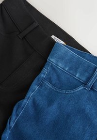 Twee paren broek: één zwart en één blauw denim. De zwarte broek heeft een soepele textuur, terwijl de blauwe een vervaagd uiterlijk en zichtbare stiksels heeft.