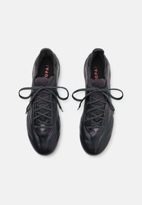 Black athletic shoes with smooth synthetic material, narrow design, rounded toes, and grey laces. Red accents on branding and upper.