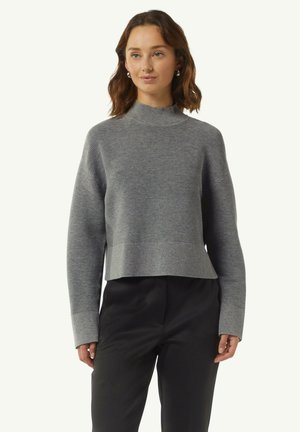 Gray cropped sweater with a mock neck, featuring horizontal stripes, ribbed cuffs, and a textured finish. Worn with black trousers.