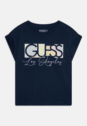 Tumedat sinine lühikeste varrukatega T-särk, mis on valmistatud orgaanilisest puuvillast ja millel on keskel suur mitmevärviline "GUESS" logo koos kalligraafilise "Los Angeles" tekstiga.