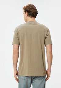 Khaki bomulds t-shirt med korte ærmer, rund halsudskæring og en afslappet pasform. Glat tekstur, ingen synlige mønstre eller detaljer.