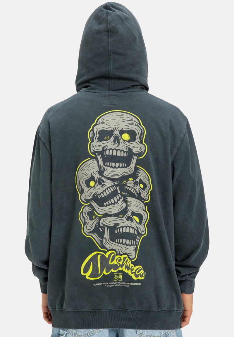 Tmavohnedá mikina s kapucňou. Na zadnej strane je grafika štyroch lebiek v žltej a sivej farbe. Čierne a žlté logo značky na spodnej strane. Materiál: bavlna.