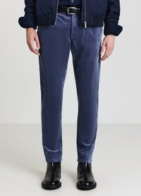 Pantaloni in corduroy blu navy con superficie testurizzata, design slim fit, abbinati a stivaletti neri alla caviglia. La vita presenta una cintura nera.