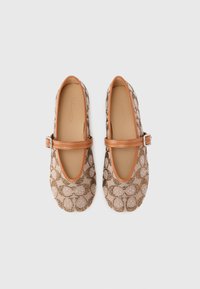 Beige ballet flats with a patterned textile upper featuring interlocking circles, finished with a brown leather strap and trim.