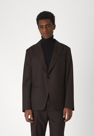 Brown pinstripe suit jacket with single button closure, notched lapels, and two front pockets, paired with a black turtleneck.