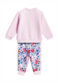 Světle růžová mikina s dlouhými rukávy a žebrovanými manžetami, doplněná o vzorované tepláky s vícebarevným květinovým motivem a žebrovanými lemy.