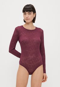 Burgundi hosszú ujjú bodysuit, texturált, absztrakt mintával. Kerek nyakkivágással és testhezálló fazonnal rendelkezik a karcsú megjelenés érdekében.