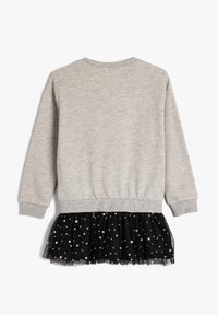 Felpa grigia con maniche lunghe e un drappo di tulle nero sull'orlo, caratterizzata da motivi di stelle colorate incorporati nel materiale.