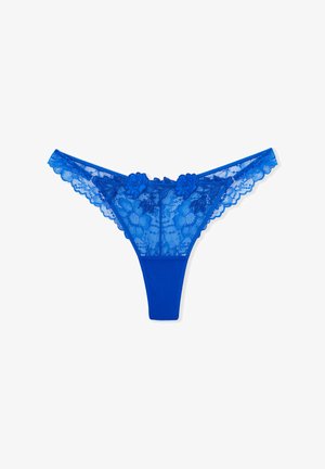 String en dentelle bleue avec des accents floraux, bords festonnés et un panneau avant en tissu lisse. Présente des motifs délicats et une texture transparente.