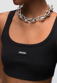 Zwarte geribbelde tanktop met een vierkante halslijn en een label met "WRSTBVR." Gecombineerd met een chunky zilveren ketting met glanzende schakels.
