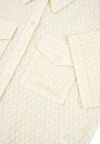 Chemise texturée crème présentant un motif en grille, un col pointu, deux poches à rabat et des boutons en perles.