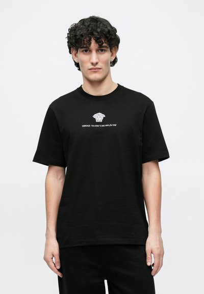 Μαύρο βαμβακερό t-shirt με κοντά μανίκια, που διαθέτει λευκή εκτύπωση λογότυπου και στρογγυλή λαιμόκοψη. Λεπτή υφή, άνετη γραμμή, μινιμαλιστικός σχεδιασμός.