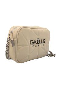 Borsa a tracolla in pelle beige con motivo trapuntato, zip argentata, tracolla in catena metallica e logo "GAËLLE PARIS" sul fronte.