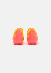 Scarpe da calcio giallo brillante e rosa con una tomaia liscia in materiale sintetico, caratterizzate da motivi a zigzag e un design a profilo basso per l'agilità.
