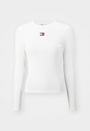 Camisa de manga longa branca em ribana, com um pequeno logótipo "Tommy Jeans" vermelho, branco e azul no peito. Tecido suave com um design ajustado.