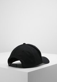 Svart baseballcap laget av stoff, med en buet skygge, justerbar stropp bak, og et enkelt design uten logoer eller mønstre.