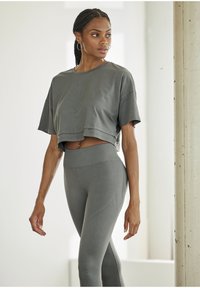 Gray cropped t-shirt with short sleeves and subtle logo, paired with high-waisted gray leggings featuring textured accents and seamless design.