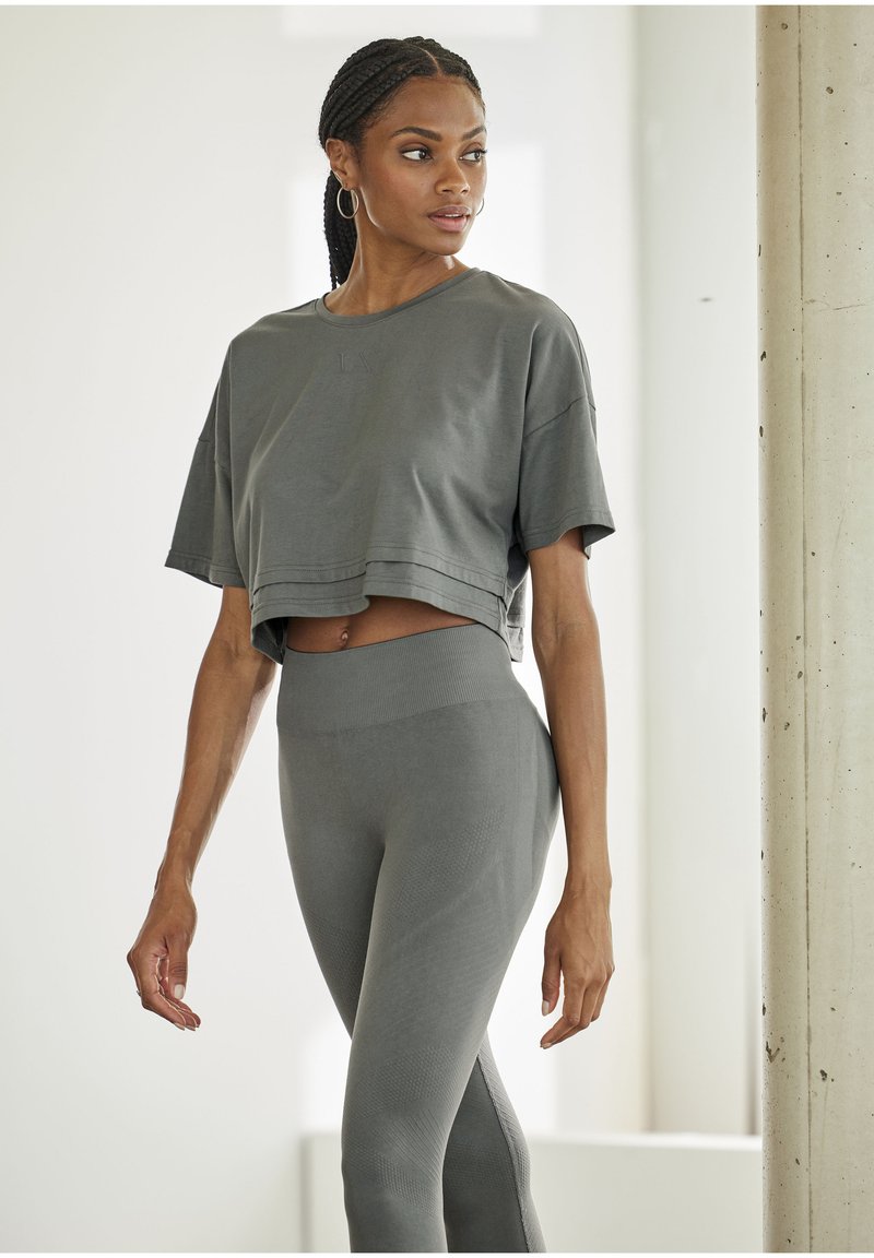 Gray cropped t-shirt with short sleeves and subtle logo, paired with high-waisted gray leggings featuring textured accents and seamless design.