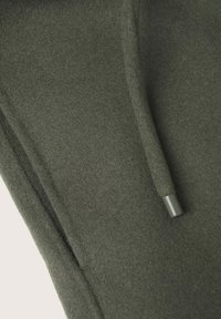 Gros plan d'un tissu polaire gris avec un cordon de serrage doté d'un embout en plastique.