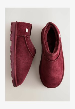 Burgunderfarvede suede ankelstøvler med et blødt fur-foer, rund tå og struktureret gummisål. Har en sidesøm og et logo-mærke.