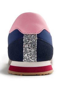 Sneaker sportivo con tomaia in pelle rosa, lati in tessuto blu navy, striscia glitterata grigia e accenti rossi sulla suola. Sono evidenti materiali testurizzati.
