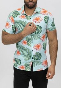 Chemise à manches courtes bleu clair, ornée d'un motif floral d'hibiscus orange et de feuilles de palmier vertes. Design à boutons avec une texture lisse.