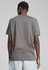 Grå kortærmet t-shirt lavet af blød bomuld, med Rund hals og rene linjer. Båret med lyseblå denimshorts.