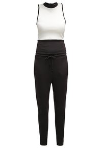 Combinaison sans manches noir et blanc avec col montant, taille à cordon et pantalons ajustés sur fond blanc.