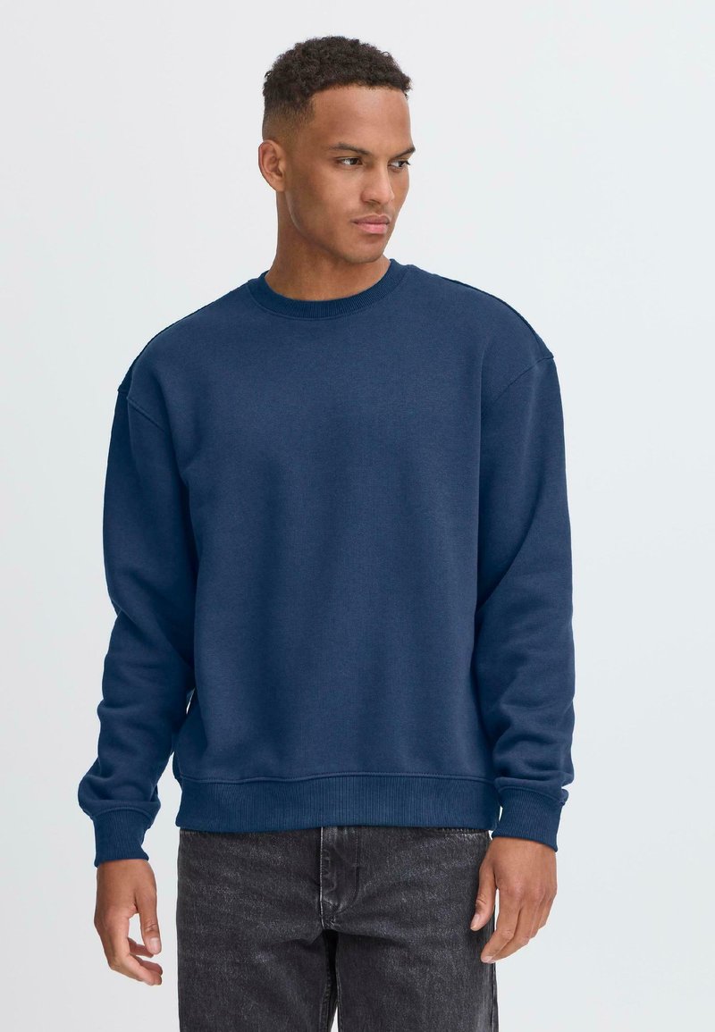 Sudadera azul marino con cuello redondo, hecha de una mezcla de algodón texturizado, con puños y dobladillo acanalados, y un ajuste relajado.