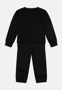Ensemble en sweat-shirt noir et pantalon assorti en tissu doux. Présente des poignets et une taille côtelés avec des ouvertures élastiquées au niveau des chevilles. Design simple.