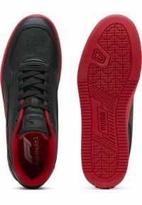 Sorte lædersneakers med røde detaljer, der har en perforeret tå, sorte snørebånd og en tekstureret rød gummisål. Puma-branding er synlig.