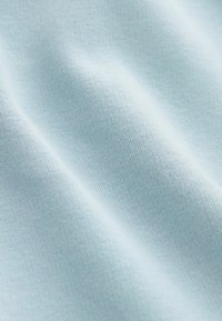 Tessuto blu chiaro con una superficie liscia, caratterizzato da un motivo a maglia. La superficie presenta variazioni sottili di tonalità e una leggera lucentezza.