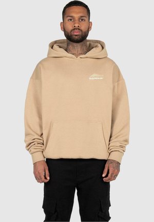 Beige hettegenser med lomme foran, ribbede mansjetter og logo-detalle på brystet. Myk stoff med en avslappet passform.