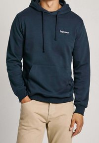 Felpa blu navy con tasca a marsupio, cappuccio regolabile con cordino e logo white "Pepe Jeans" sul petto. Materiale morbido in misto cotone.