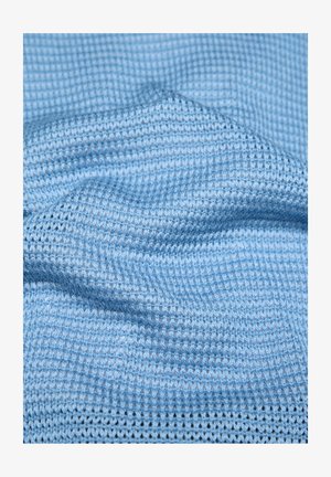 Light blue knitted fabric with a textured waffle pattern, showing gentle folds and soft material details.