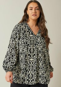 Sort og creme mønstret bluse med V-hals og puffede ærmer. Har abstrakte designs og en afslappet pasform. Fremstillet af letvægtsstof.