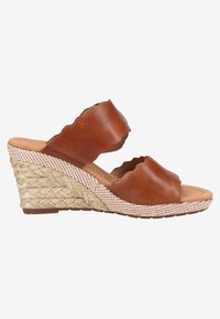 Sandale compensée en cuir marron avec bords festonnés et talon plateforme en paille tressée, bout ouvert et style slip-on sur fond uni.